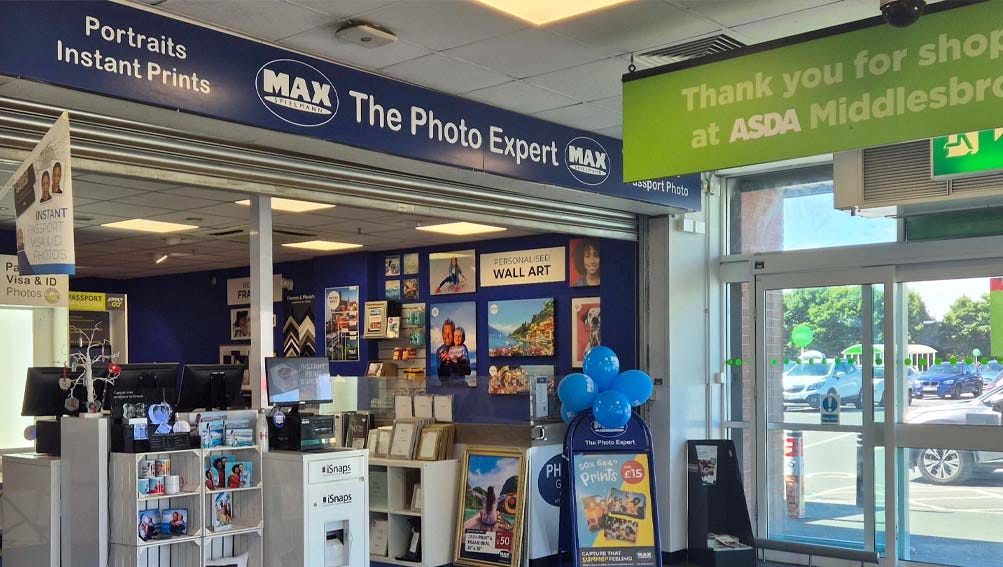 A photo shop exterior featuring a prominent sign that reads "The Photo Expert," inviting customers to explore photography services.